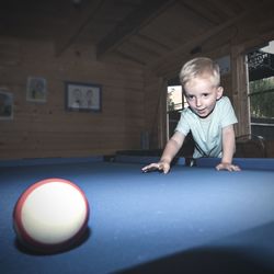 Smiling boy looking at ball on pool table