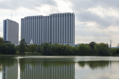 Reflection of building in lake against sky in city