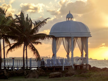 Built structure by sea against sky during sunset