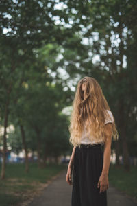 Girl with tousled hair standing against trees