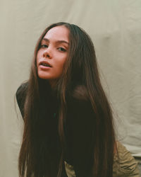 Portrait of beautiful young woman against beige backdrop