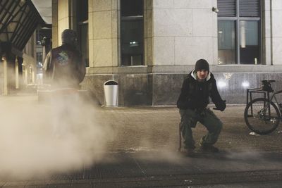 Full length of man sitting on sidewalk during foggy weather