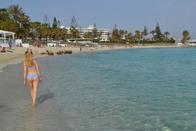 Rear view of a bikini woman walking on beach