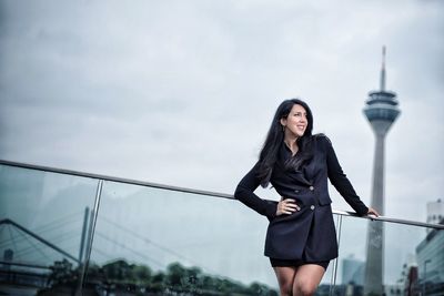 Woman standing by railing against tower