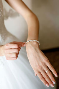 A girl with an elegant bracelet on her hand on the background of the wedding dress