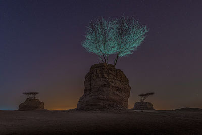 Low angle view of rock formation on field against sky at night
