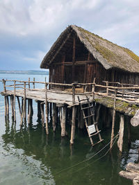 Wooden house by sea against sky