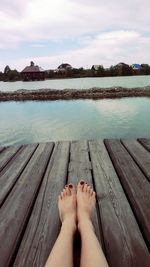 Low section of man on pier over lake against sky