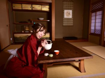 Young woman sitting on table at home