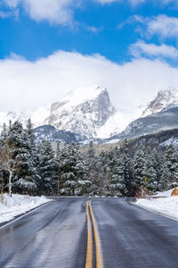 Road by snowcapped mountains against sky