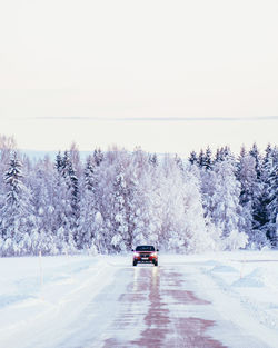 Car on snow covered road against sky