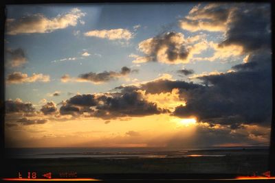 Scenic view of sea against cloudy sky during sunset