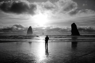 Silhouette man standing at beach against sky during sunset