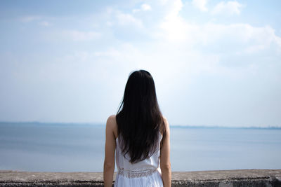 Rear view of woman looking at sea against sky