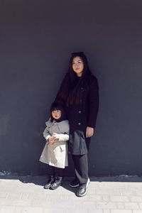 Koreans mom and daughter stand at the black wall in spring