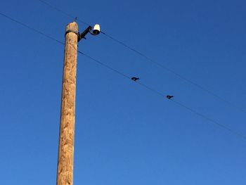 Low angle view of power lines against blue sky