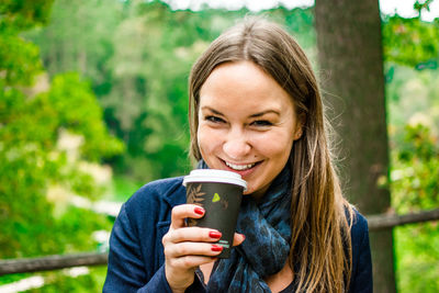 Portrait of cheerful young woman drinking coffee
