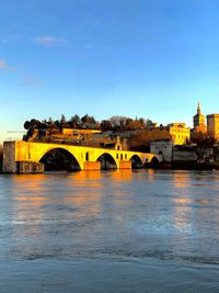 Arch bridge over river against blue sky
