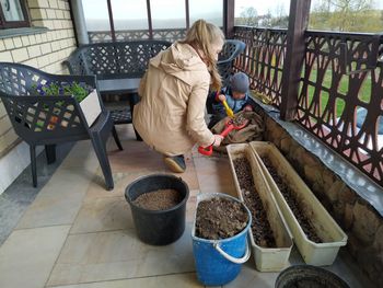 Mom and little son transplant flowers of surfinia on the terrace