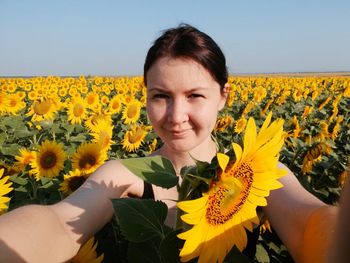 Portrait of woman with yellow flower on field