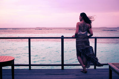 Full length of woman standing by railing against sea