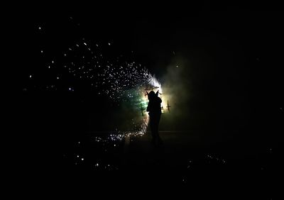 Silhouette man standing against illuminated ferris wheel at night