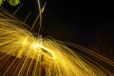 Low angle view of person spinning illuminated wire wool at night