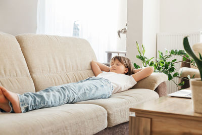 Happy teenage girl, schoolgirl is resting in the room on a comfortable sofa. child lies and dreams