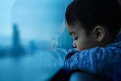 Profile view of boy looking through window during sunset