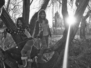 Portrait of happy friends standing on tree at park