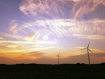 Windmill on field against sky during sunset