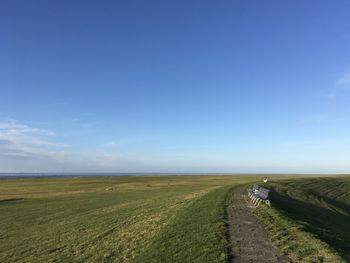 Road passing through field against sky