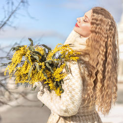 A woman with a bouquet of yellow acacia flowers. spring holiday - march 8, easter, women's day