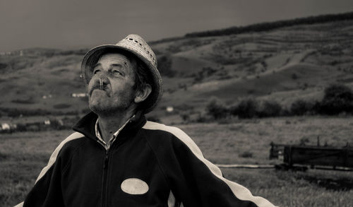 Man wearing hat smoking cigarette against mountain