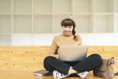 Young woman using phone while sitting on table