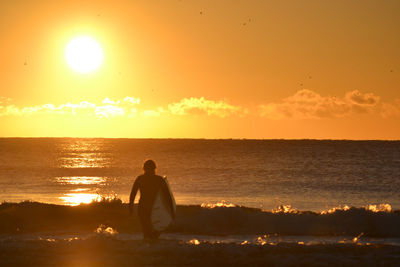 Man looking at sea against sky during sunset