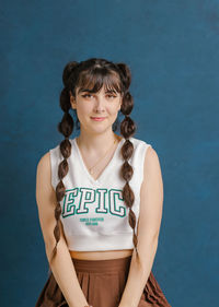 Portrait of young woman standing against blue background