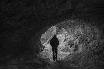 Rear view of silhouette mid adult man standing in cave