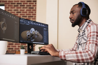 Side view of man using laptop at office