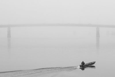 Man on boat in sea against sky during foggy weather