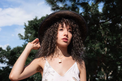 Portrait of beautiful young woman against trees