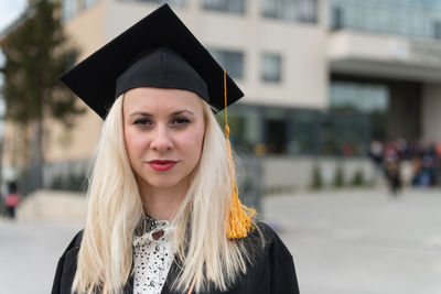 Young woman wearing graduation gown standing outdoors
