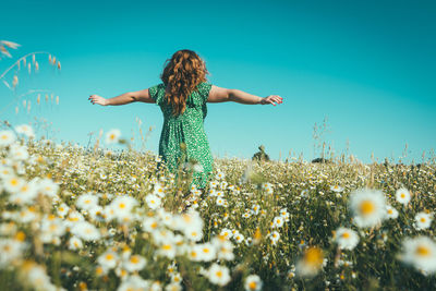 Full length of woman with pink flowers on field against sky