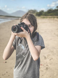 Midsection of woman photographing on beach