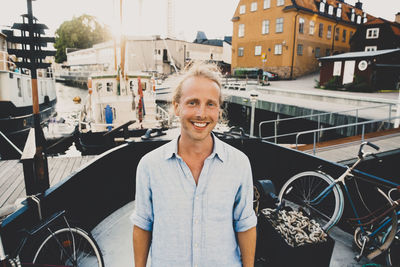 Portrait of smiling man standing on bicycle in city