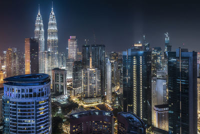 Illuminated buildings in city against sky at night