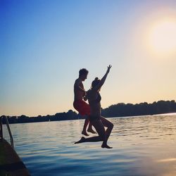 Silhouette of woman jumping at sunset