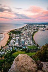 High angle view of buildings by river against cloudy sky