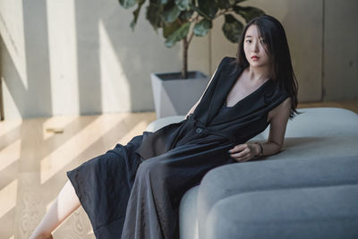 Young woman looking away while sitting on sofa at home