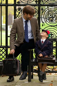 Smiling father with cute son sitting on bench